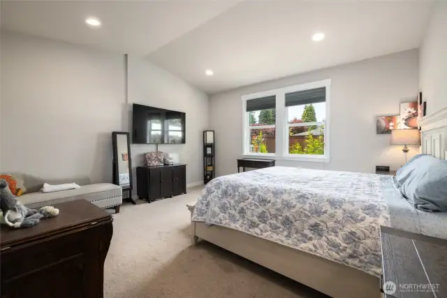 The primary bedroom has lots of space for furniture and a vaulted ceiling.