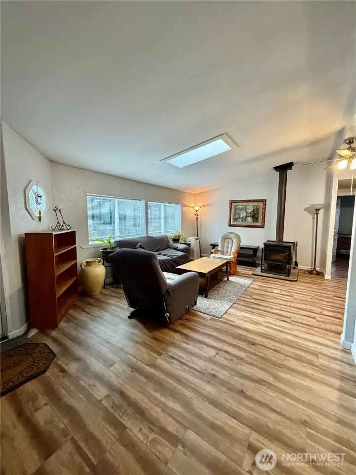 Spacious living room area with skylight and wood burning stove.