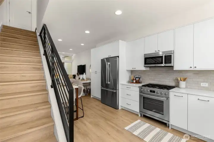 The kitchen and living areas connect with effortless flow, anchored by hardwood floors and designer lighting.