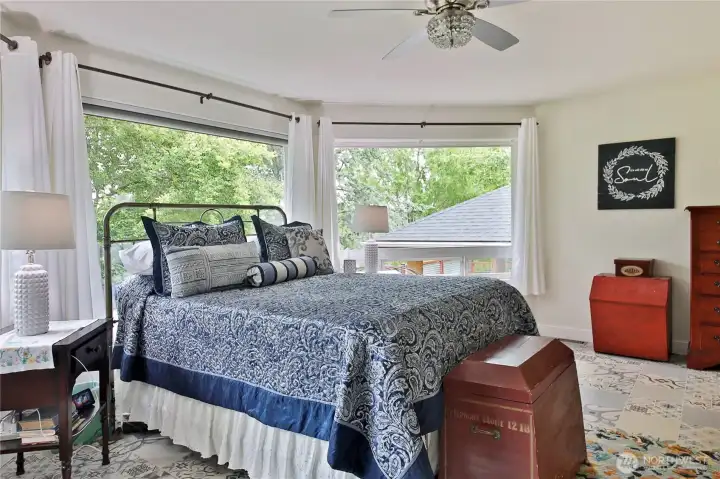 You'll find the primary bedroom is a nice size. Bright cork flooring and a wall of windows, surrounded by trees.