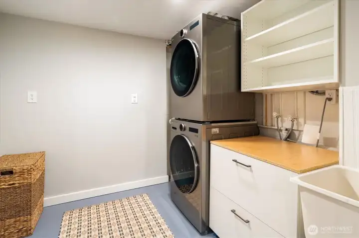 Great laundry room with stainless steel washer and dryer, a folding station and utility sink.