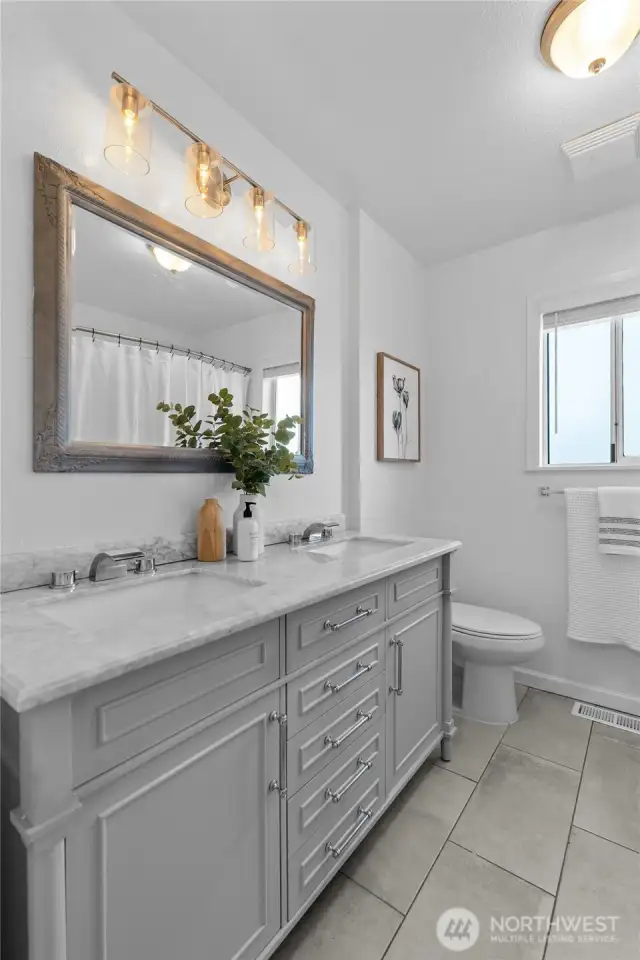 BATHROOM | The main bathroom in the home features double sinks, a tub and shower. New light fixtures make the space sparkle.