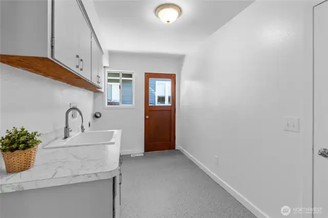 LAUNDRY/MUD ROOM | With Marmoleum flooring and a deep utility sink, this room is functional and bright. The door leads to the right side of the home.