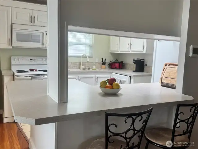 This kitchen features an eating bar, and to the left is the dining room. This entire area opens up to the living room with pellet stove, huge view windows showing the waterfront and the backyard with its beautiful waterfront seating.