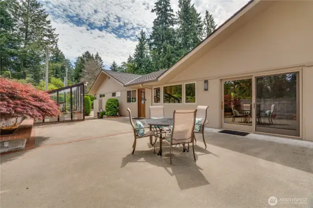 Side patio off the kitchen & main level great room has lake views.  Gas grill hookup, greenhouse and seating around concrete planters.