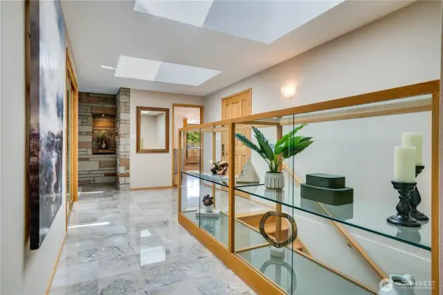 Main level hallway, front door to the right.  Kitchen & nook to the right, Living room & dining room to the left.  Custom display case for collectibles with skylights above.