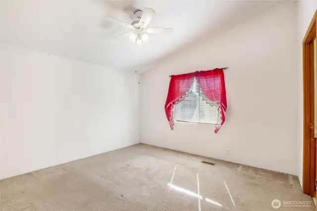 Primary bedroom with blinds, ceiling fan, and lovely curtains.  The bathroom is the door to the right.