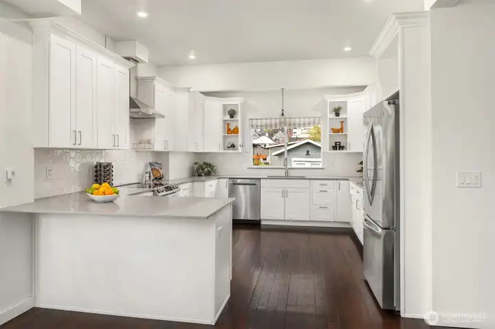 The thoughtfully updated, grand Chef's kitchen boasts sleek Quartz countertops, quality appliances include a newer fridge, induction stovetop, dishwasher, and ample cabinetry, and quiet-close, dovetailed wood drawers.