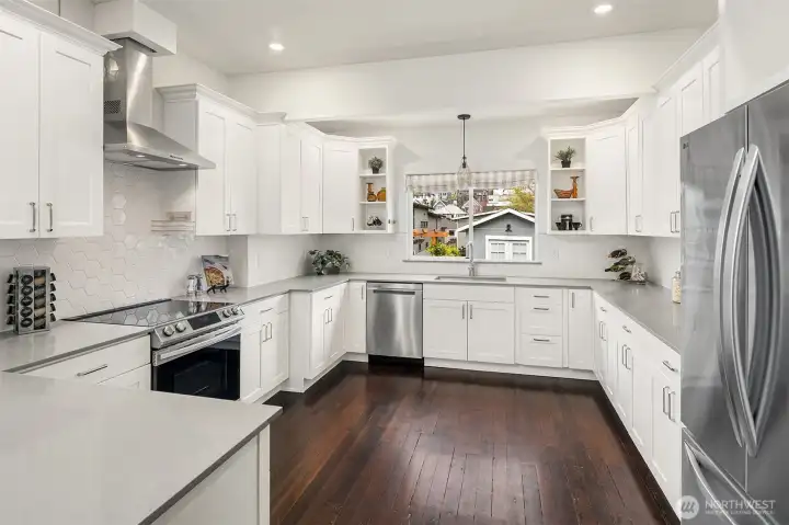The thoughtfully updated, grand Chef's kitchen boasts sleek Quartz countertops, quality appliances include a newer fridge, induction stovetop, dishwasher, and ample cabinetry, and quiet-close, dovetailed wood drawers.
