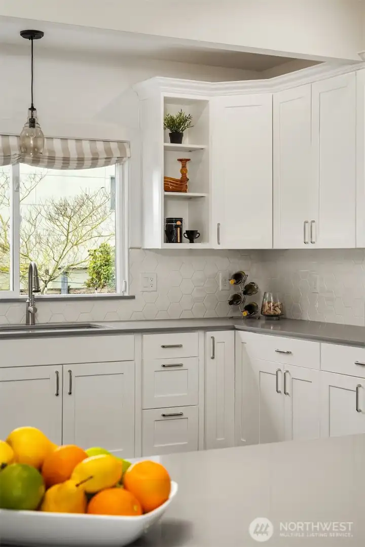 The thoughtfully updated, grand Chef's kitchen boasts sleek Quartz countertops, quality appliances include a newer fridge, induction stovetop, dishwasher, and ample cabinetry, and quiet-close, dovetailed wood drawers.