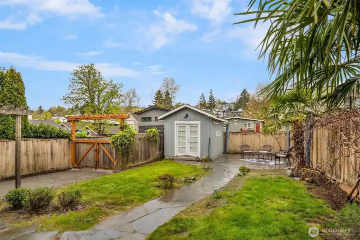 Large, fenced-in backyard with flagstone patio, shed, and lush landscaping offers a private urban oasis.