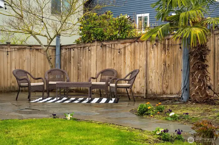 Large, fenced-in backyard with flagstone patio, shed, and lush landscaping offers a private urban oasis.