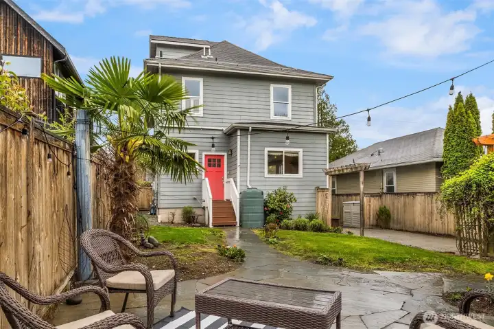 Large, fenced-in backyard with flagstone patio, shed, and lush landscaping offers a private urban oasis.
