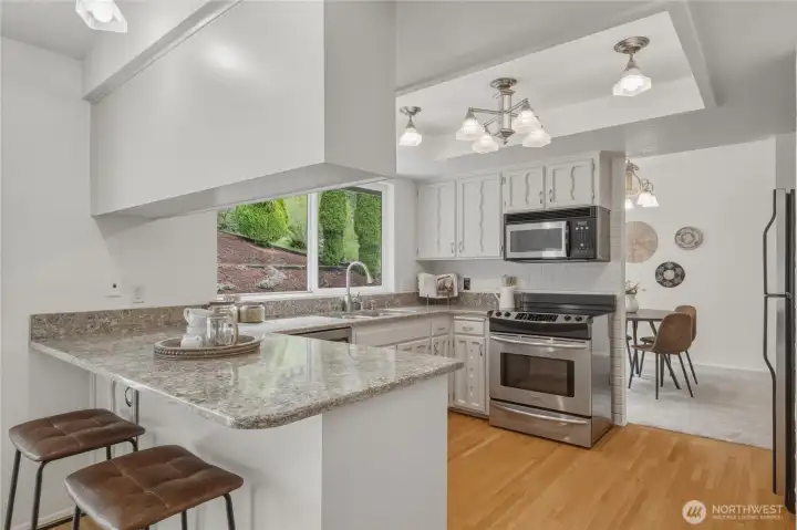 The kitchen features stainless appliances and an eating bar