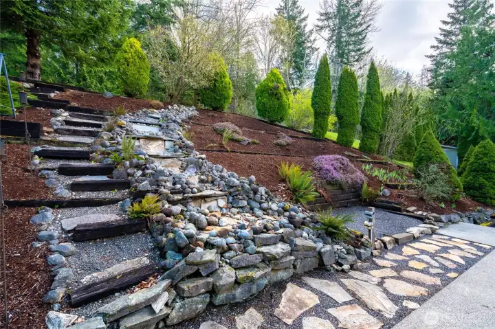The gorgeous backyard landscaping with water feature and stairs to the upper yard.