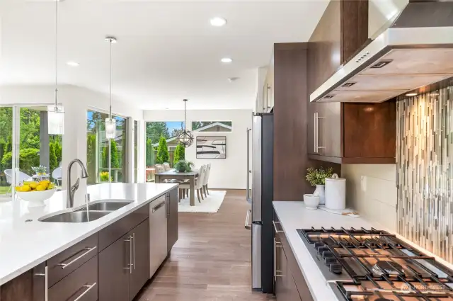 Kitchen boasts full-height backsplash, soft-close drawers, 5-burner gas stove, and stainless steel appliances.