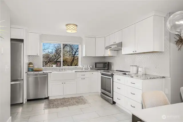 This remodeled kitchen features beautiful stone counters, tile floor, and stainless steel appliances.