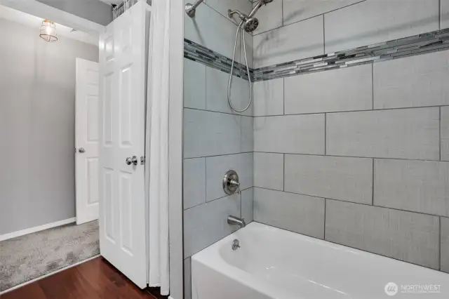 Custom tile work surrounds the shower/tub.