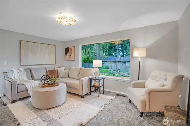 The upper-level living room boasts of a large picture window overlooking the delightful yard.