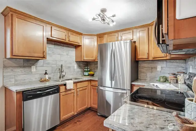 This efficient U-shaped kitchen has everything you need at your fingertips. Rich cabinetry is complemented by granite countertops and a lovely tile backsplash.