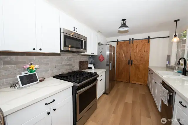 Sleek, newly updated kitchen. Slider barn doors cover the pantry.