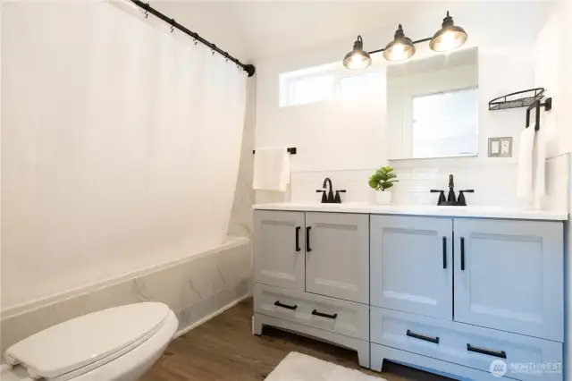 The primary bathroom features double sinks, new tile, and new fixtures