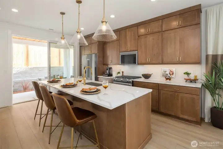 Warm wood finish cabinetry with brass accents. Elegant full height cabinets in kitchen.