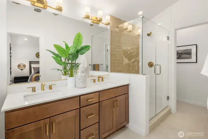 Primary bath with dual sinks and fully tiled shower with frameless glass enclosure.