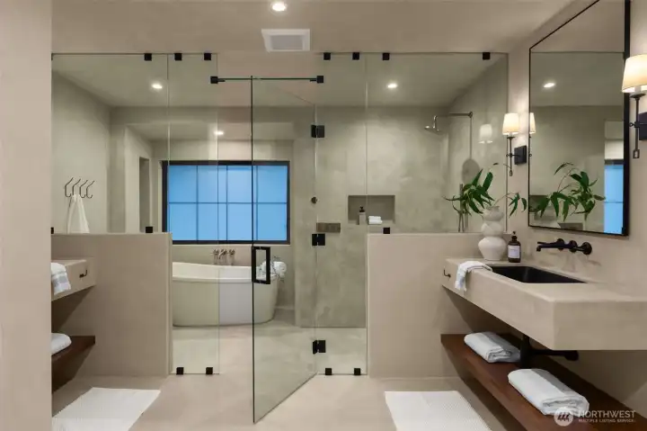 Elegant primary suite bath impresses with a glass shower enclosure with a freestanding tub and floating vanities