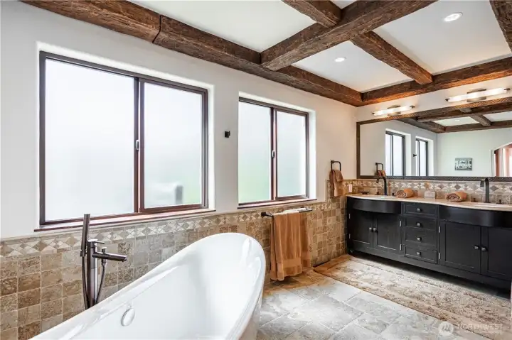 Spa-inspired primary bath with soaking tub and lake views.