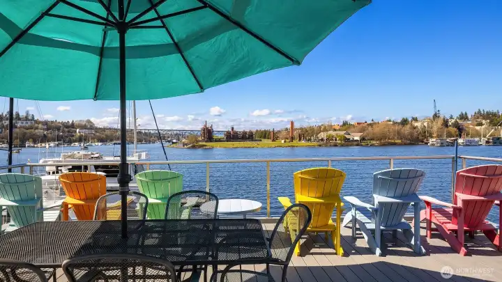 The rooftop deck umbrella open, chairs lined up along a partial glass windscreen framing the lake.