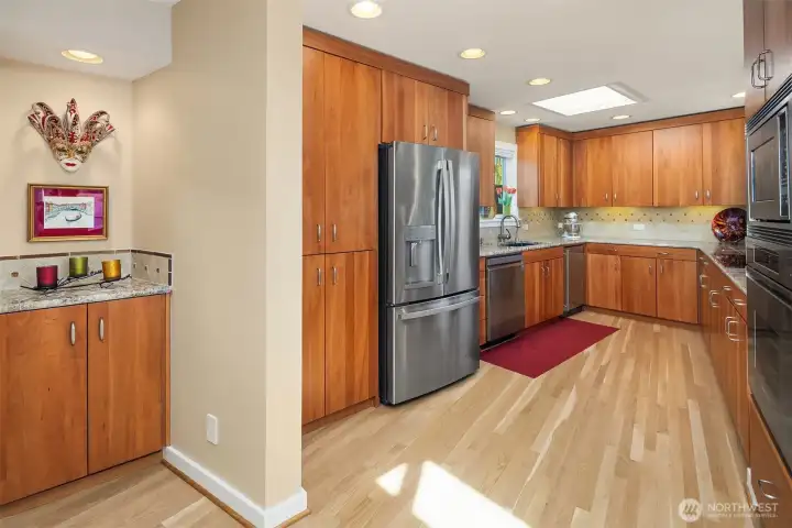 Cherry cabinetry, granite counters, and a stainless French-door fridge anchor a U-shaped kitchen that makes cooking feel effortless.