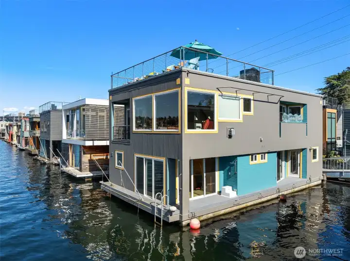 A drone's-eye sweep shows the rooftop deck in use and the home's enviable position near the head of the dock.
