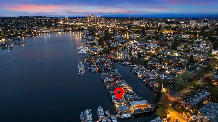A high-up aerial shows the I-5 bridge, the University District, and the dense glow of surrounding neighborhoods — a reminder of just how central this address is.