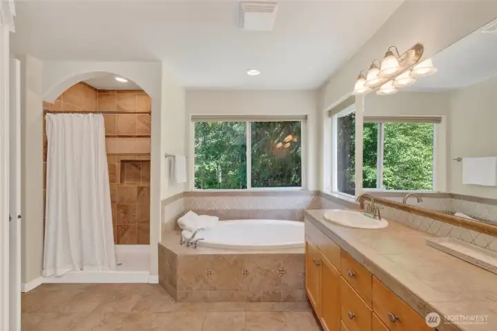 Primary bath with tiled shower and deep soaking tub.