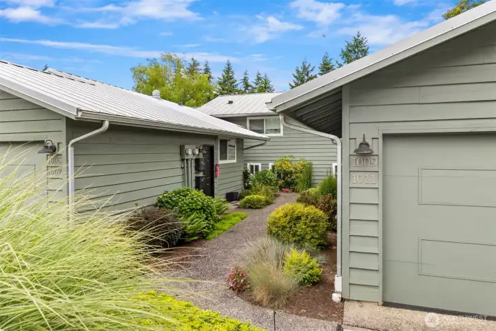 Enter on the garden path to the left of the garages. Front door is on the right.