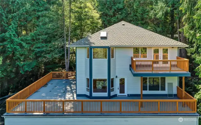 Looking south at new wrap-around Deck and Balcony at back of home. Street is hidden. Roof is newer (2006). There are skylights in both full baths on upper level.