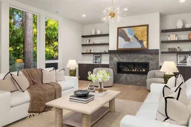Custom built-in shelves and cabinets, dual chandeliers, and a modern fireplace with TV hookup.