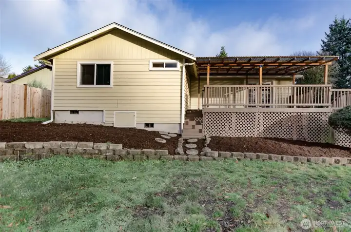 Side view of home has terraces landscaping and oversized covered deck.