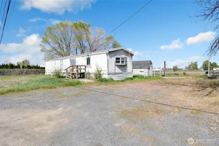 Driveway and parking for the single wide trailer.  A shed is behind the trailer.
