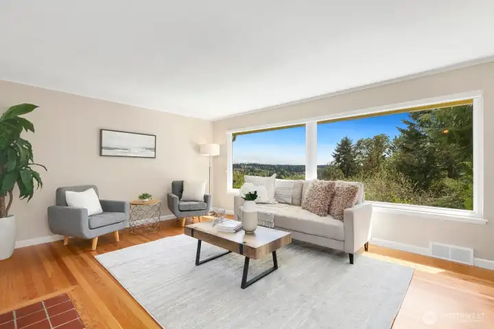 Open living and dining layout with oversized windows, hardwood floors, and treetop views on two sides.