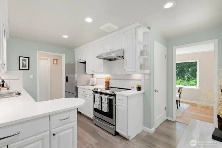 Bright galley-style kitchen with ample cabinetry, under-cabinet lighting, and stainless dishwasher.