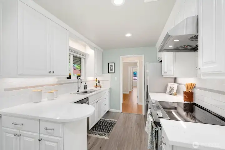 Updated kitchen featuring white shaker cabinets, quartz countertops, stainless appliances, and subway tile backsplash.