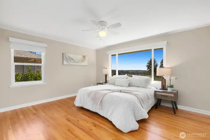 Spacious primary bedroom with refinished hardwood floors, ceiling fan, and stunning territorial views, including Rainier.