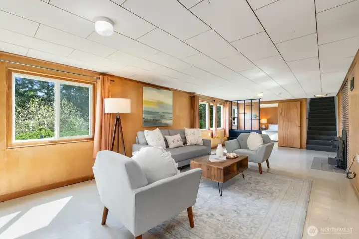 Generous lower-level rec room with wood paneling, multiple windows, and staircase access for great flex space.