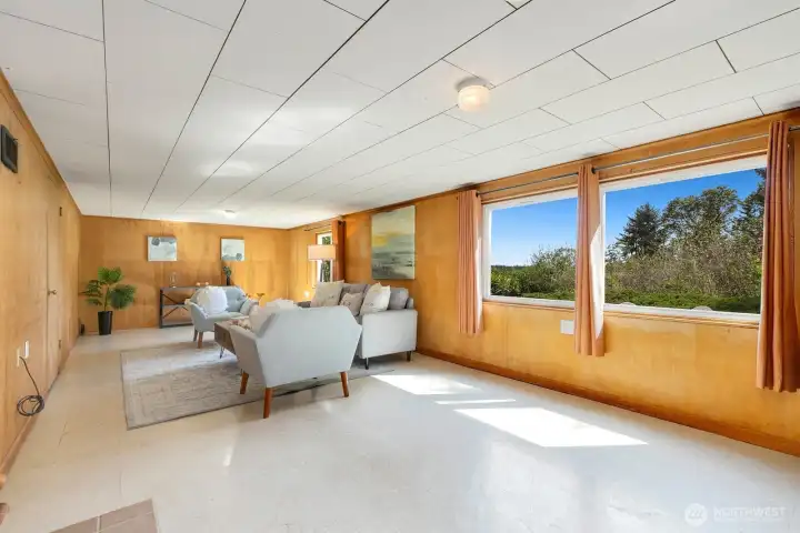Spacious lower-level rec room filled with natural light and tree-framed views through large windows.