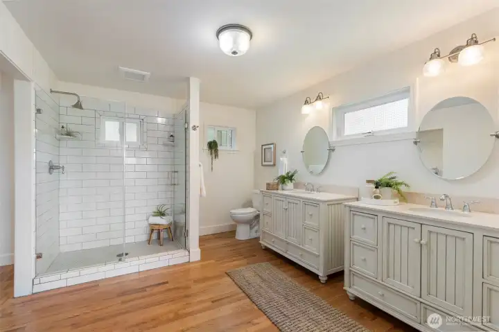 En suite Primary bath with double sinks and large tiled shower with a large walk in closet