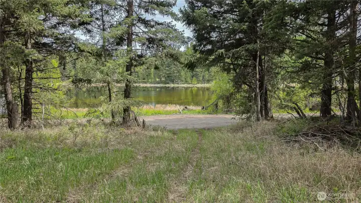 Your entrance with Teal Lake just across the street! This established, wooded pathway offers a perfect, framed view of the east-facing waterfront, waiting for your dream home behind in the feild.