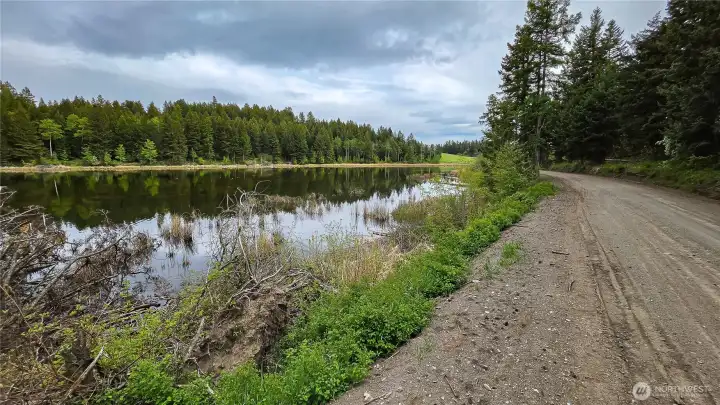 Looking south down Davies Road. Enjoy stunning views of Teal Lake right from the approach! This county-maintained route guarantees reliable, year-round access to the property, making winter visits and future construction logistics an absolute breeze.