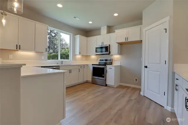 Beautiful open kitchen featuring quartz counters tile backsplash and stainless appliances. Walk in pantry on the right door.